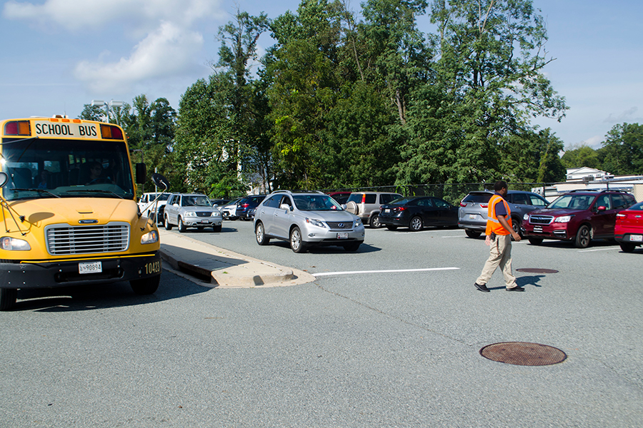 Students rush out of the back lot at the end of school, while being directed by security. Administration updated how parking passes are distributed to students, cutting the application window from two weeks to one starting this year.