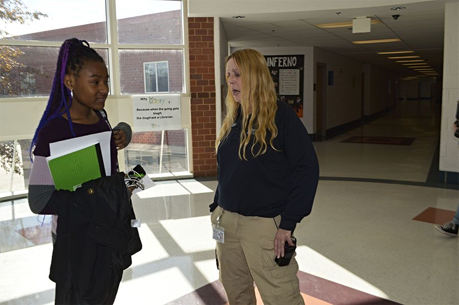 Security guard Kelly McDonnell talks to junior Jalinn Brooks as they pass in the rotunda hallway in between classes.  