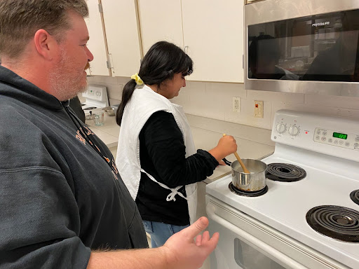 Mr.Lomax instructing students on how to mix ingredients.