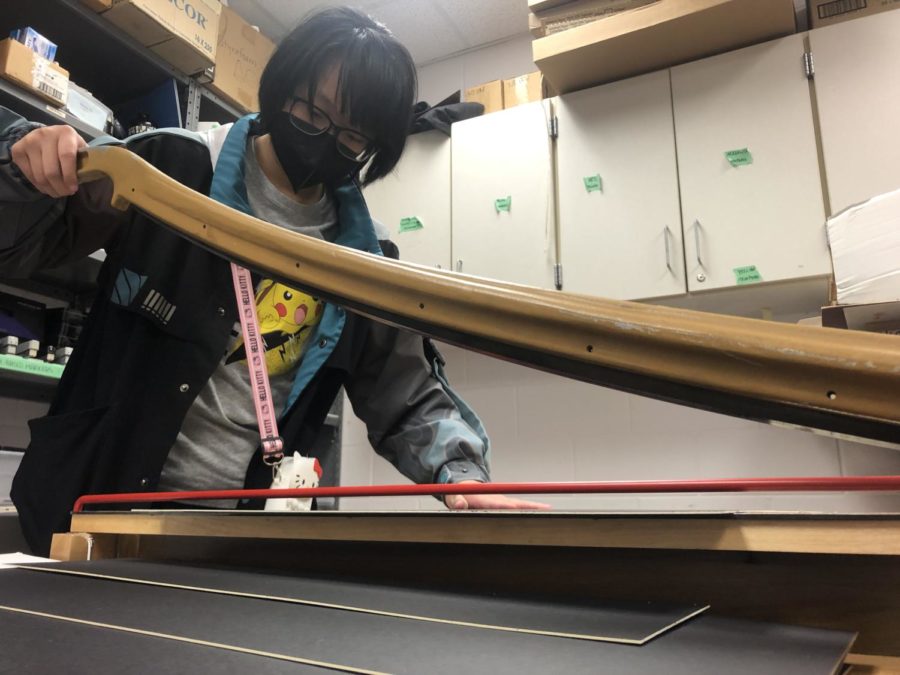 IB Art and Design student Seven Chang cutting matboard for their IB art exhibition.
