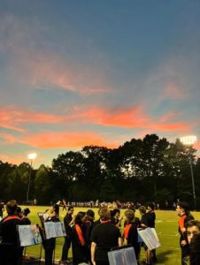 The RHS marching band performs on the track during a Friday night football game.